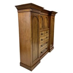 Victorian mahogany break front triple wardrobe, the projecting cornice over one central cupboard with two doors and two short and three long drawers, flanked by two cupboard doors opening to reveal interior fitted for hanging, raised on a plinth base
