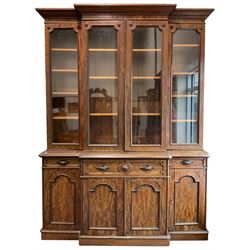 A. Blain & Son Liverpool - mid-to Late Victorian figured mahogany break-front bookcase on cupboard, projecting moulded cornice over plain frieze, four glazed bookcase doors enclosing shelves with flowerhead carved roundel mounts, the moulded top over central secretaire drawer fitted with satinwood drawers and pigeon holes, flanked by shallower drawers, the drawer fronts with foliate carved handles, cupboards below enclosed by stepped arch panelled doors, on moulded plinth base, the drawers and doors stamped 'A. Blain & Son Liverpool'