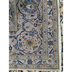 Persian Kashan ivory and wheat ground carpet, shaped floral design medallion surrounded by scrolling leafy branches and stylised plant motifs, multiple band border, the main band with scrolling branches and interspersed with flowerheads