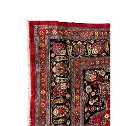 Persian Kashan crimson ground carpet, the central indigo pole medallion surrounded by sparsely placed bouquets interconnected with foliate branches, the guarded border with repeating palmette and Boteh motifs with interwoven scrolling patterns