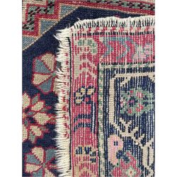 Caucasian red ground rug, the field divided into three panels each with large floral design medallions, repeating guarded border
