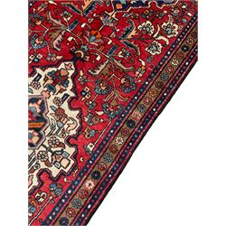 Persian Hamadan red ground runner, the field decorated with triple floral design medallions surrounded by trailing stylised plant motifs, the border decorated with repeating flower heads
