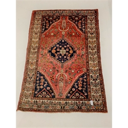 Persian red ground rug, with lozenge medallion on field decorated with stylised geometric floral design, enclosed by border, 200cm x 134cm