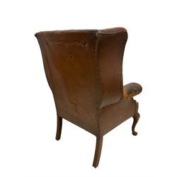 Wingback armchair, upholstered in brown leather, raised on cabriole supports 