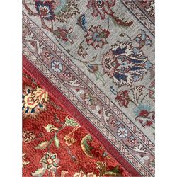Persian Meshed golden red ground carpet, central rosette medallion in field of trailing branch and stylised plant motifs, shaped spandrels with medallions, triple band border, the main band decorated with stylised flower head motifs 