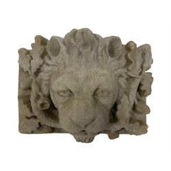 Composite stone wall plaque of a lion mask, mouth slightly agape, surrounded by oak leaves and acorns