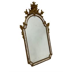 Gilt cushion framed wall mirror, the shell and flower head pediment with extending floral decoration, scrolled foliate detail to uprights, plain mirror plates with moulded inner slip
