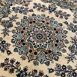 Persian Ardakan ivory ground rug, the field decorated with a large central lotus medallion surrounded by garlands of flowers, the triple-band border with symmetrical floral bouquet designs with indigo outlines