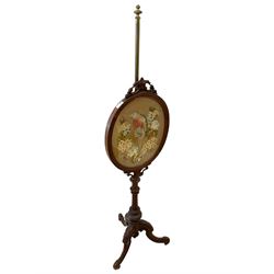 Victorian walnut and brass pole screen, the oval moulded frame with foliate C-scroll pediment enclosing needlework panel, turned and fluted column, on three foliage carved splayed supports with scrolled terminals