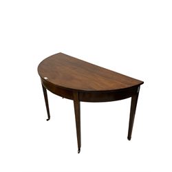 George III mahogany demi lune side table, raised on square tapering supports, terminating in brass castors 