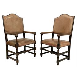 Pair oak open armchairs, high shaped arch back, upholstered in tan leather with studded bands, turned supports and front stretcher, joined by a series of plain stretchers