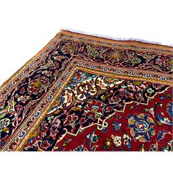 Persian Kashan crimson ground rug, the central pole lozenge medallion surrounded by all-over interlacing floral patterns, the heavily guarded indigo border with repeating palmette motifs connected by trailing leafage