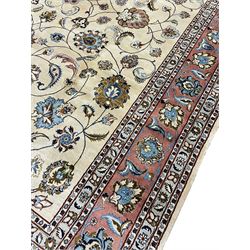 Persian Meshed ivory ground carpet, the field decorated with interlaced branches and stylised plant motifs with birds, peach ground scrolling border with repeating floral motifs within guard bands