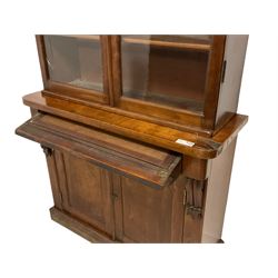 Victorian mahogany bookcase on cupboard, projecting cornice over two glazed doors enclosing shelves, mounted by scroll and acanthus carved brackets, fall front drawer over panelled double cupboard, on chamfered plinth base 