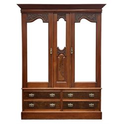 Edwardian figured walnut double wardrobe, enclosed by bevelled mirror glazed doors with foliate carvings, fitted with four drawers, on skirted base