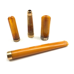 Four amber cheroot holders, one with 9ct rose gold mounts, another with silver mount and two others with rolled gold mounts (4)