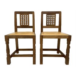 Mouseman - set four oak dining chairs, lattice carved back, upholstered in tan leather with studded band, the octagonal front supports carved with mouse signatures, by the workshop of Robert Thompson, Kilburn