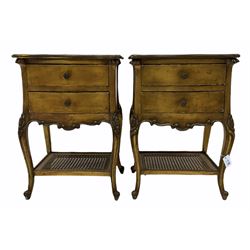 Pair French style gilt bedside tables, the shaped moulded tops over two drawers and shaped apron, floral carved cabriole supports joined by cane under tier 