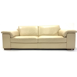Contemporary three seat sofa, upholstered in cream faux leather, raised on walnut block supports, W235cm, H84cm, D102cm