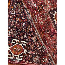 Persian Qashqai red ground rug, the extended lozenge field decorated with a central pole medallion comprised of three connecting diamonds, surrounded by all-over flower heads and stylised plant motifs, the multi-band border with repeating geometric shapes and Boteh motifs