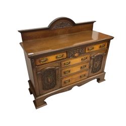 Edwardian walnut and oak sideboard, raised back with dentil carving and central shell motif, fitted with six assorted drawers and two flanking cupboards, the panelled facias carved with cartouche shields and scrolling foliage, on bracket feet