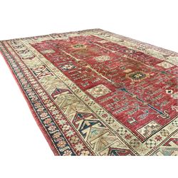 Afghan Kazak crimson ground rug, the field decorated with stylised geometric tree and animal motifs and octagonal and rectangular shapes enclosing stars, the multi-band ivory border with repeating shapes and stylised flower heads