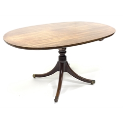 Georgian mahogany breakfast table, oval tilt top on turned pedestal base, four out splayed supports with brass cups and castors, 133cm x 96cm, H72cm