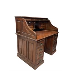 20th century mahogany roll top desk, the tambour top enclosing fitted interior over six short and one long drawer, raised on a plinth base, together with oak roll top desk of similar design 