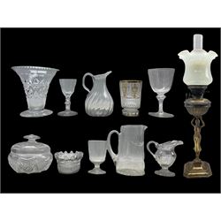 19th century clear glass jug of fluted wrythen form with folded rim H17cm, 19th century Bohemian cut glass beaker with gilt decoration, 19th century wine glass with a faceted stem, Victorian figural brass oil lamp with vaseline frill glass shade and other glassware 