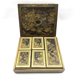 19th century Chinese black lacquer and gilt games box, of rectangular form, the body decorated with landscapes within stylised foliate borders, the cover opening to reveal an interior fitted with five lidded boxes containing mother of pearl counters, the majority engraved with the initials E.W. and the remaining engraved with Pagodas, together with stained ivory counters, L30cm, D26.5cm, H8cm 