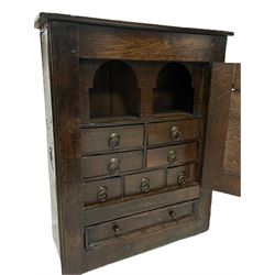 18th century oak wall hanging cupboard, enclosed by single fielded panel door, the interior fitted with seven small drawers, single drawer below