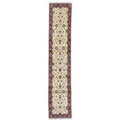 Persian Kashan ivory ground runner rug, the field decorated palmettes interlaced with scrolling foliate branches with flower heads, the crimson border with repeating floral patterns guarded with indigo bands
