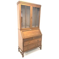 Early 20th century oak bureau bookcase, the top section with two glazed doors enclosing three adjustable shelves, over sloped fall front revealing fitted interior and inset writing surface, three long drawers under, raised on turned supports united by 'H' stretcher W100cm, H208cm, D47cm