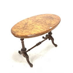 Victorian burr walnut oval centre table, the moulded quarter sawn veneered top raised on two turned, fluted and lobe carved end uprights united by turned stretcher, with four scroll carved and out splayed supports terminating in castors 