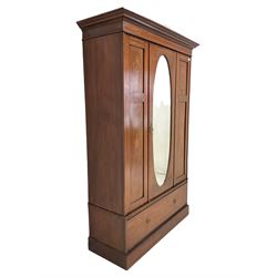 Edwardian mahogany wardrobe, the projecting cornice over single oval mirror panelled door, opening to reveal interior fitted for hanging, over one drawer, raised on plinth base 