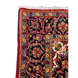 Small Persian Kashan red ground rug, the field decorated with interlacing foliage and stylised plant motifs, central indigo ground medallion, the guarded border decorated with scrolling branch and flower heads, signature to each end