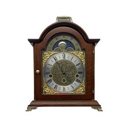 A 20th century mantle clock with a three train Hermle spring driven movement chiming the quarters and striking the hours on five gong rods, in a mahogany effect case with a break arch top and carrying handle, brass dial with matching applied spandrels and silver chapter ring, Roman numerals and a minute track, steel serpentine hands and etched dial centre, with a working moon disc in the break arch.

