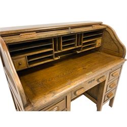 Early 20th century oak roll top knee hole desk, the tambour top enclosing fitted interior, the lower section fitted with two slides and seven drawers, raised on shaped supports