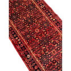 Persian red ground runner, the field decorated with repeating floral design Herati motifs, the main indigo ground border decorated with stylised flowerheads, framed within guard stripes