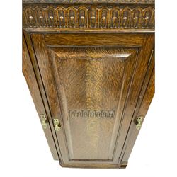 Early 20th century oak bookcase cabinet, breakfront with raised back, frieze carved with arcade decoration, fitted with two flanking astragal glazed doors and central panelled cupboard, brass handles in the shape of pharaoh masks, raised on turned supports with gadroo design, united by shaped stretcher