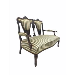 Late Victorian mahogany two seat salon settee, floral and pierce carved back rest, upholstered in stripped fabric, raised on cabriole front supports W127cm