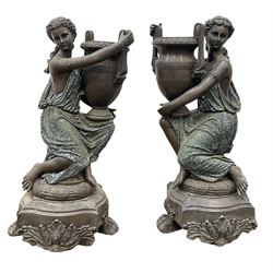 Pair statues of Classical Greek maidens holding amphorae urns with a bronzed finish, the amphorae having busts of Medusa below the handles, the maiden's dresses with a marbled finish kneeling upon a stepped foliate base with clawed feet