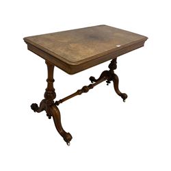 Victorian figured walnut stretcher card table table, rectangular swivel and fold-over top with moulded edge and inset baize lining, raised on turned vasiform end supports with foliate carved decoration terminating in splayed and scrolled feet with ceramic castors
