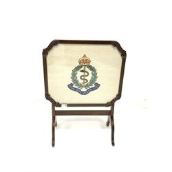 20th century mahogany metamorphic fire screen occasional table, the tilt top with glazed panel enclosing needlework of Royal Army Medical corps coat of arms 