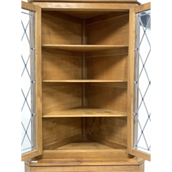 'Eagleman' oak corner cupboard,  with led glazed doors enclosing three shelves, panelled doors under enclosing another shelf, raised on block supports, W84cm, H198cm, D59cm