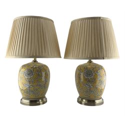 Pair of Chinese porcelain lamps, each of ovoid form, decorated with scrolling foliage against a yellow ground, raised upon circular brushed bronze base, H54cm including shade 