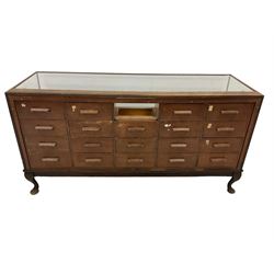 Early 20th century oak framed haberdashery shop counter, glass panel exterior enclosing sixteen graduating drawers with oak fronts and handles, raised on cabriole supports