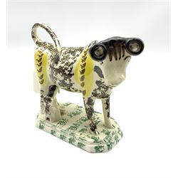19th century Pratt type cow creamer sponged in black and yellow with seated milk maid on an octagonal base H14cm x L18cm