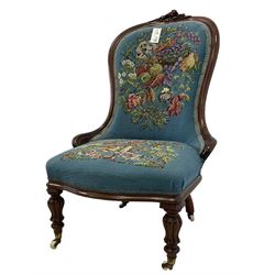 Victorian mahogany framed nursing chair, applied rose carved cresting rail, back and sprung seat upholstered in floral tapestry fabric, raised on turned lobe carved supports with ceramic castors