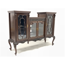 Early 20th century Georgian style mahogany display cabinet, having an incised frieze decorated with scrolled foliate over four glazed cupboard doors enclosing bevelled mirrored back and silk lined shelves, floral and shell carved serpentine apron, all raised on slender cabriole supports 